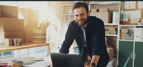 Junger Mann in seinem Online-Shop vor Paketen